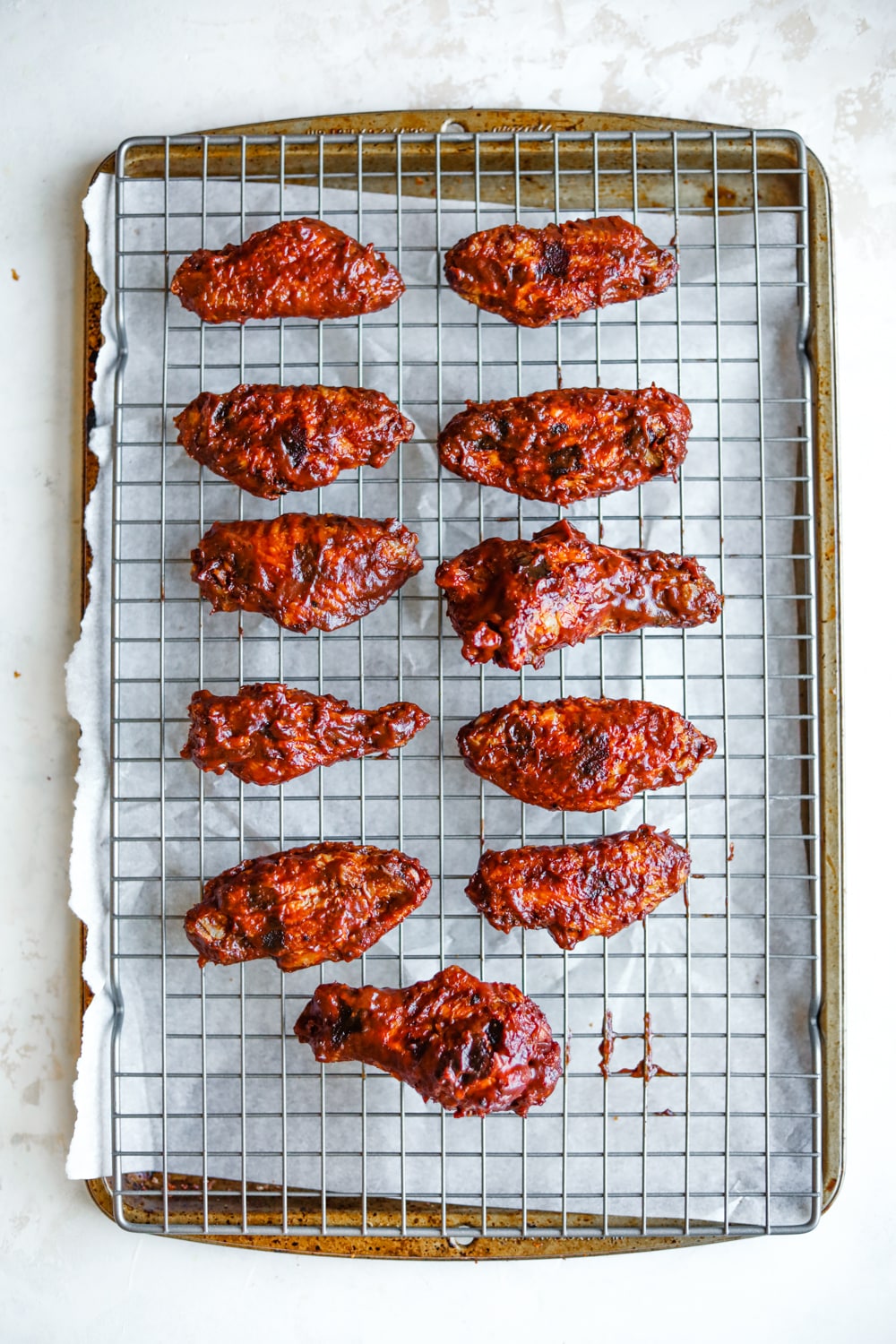 11 BBQ chicken wings on a drying rack that's set over a baking sheet.