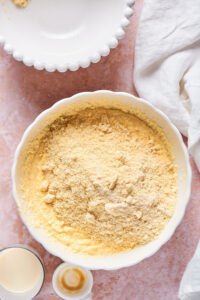 A white bowl on a pink counter filled with almond flour and coconut flour for a cake.