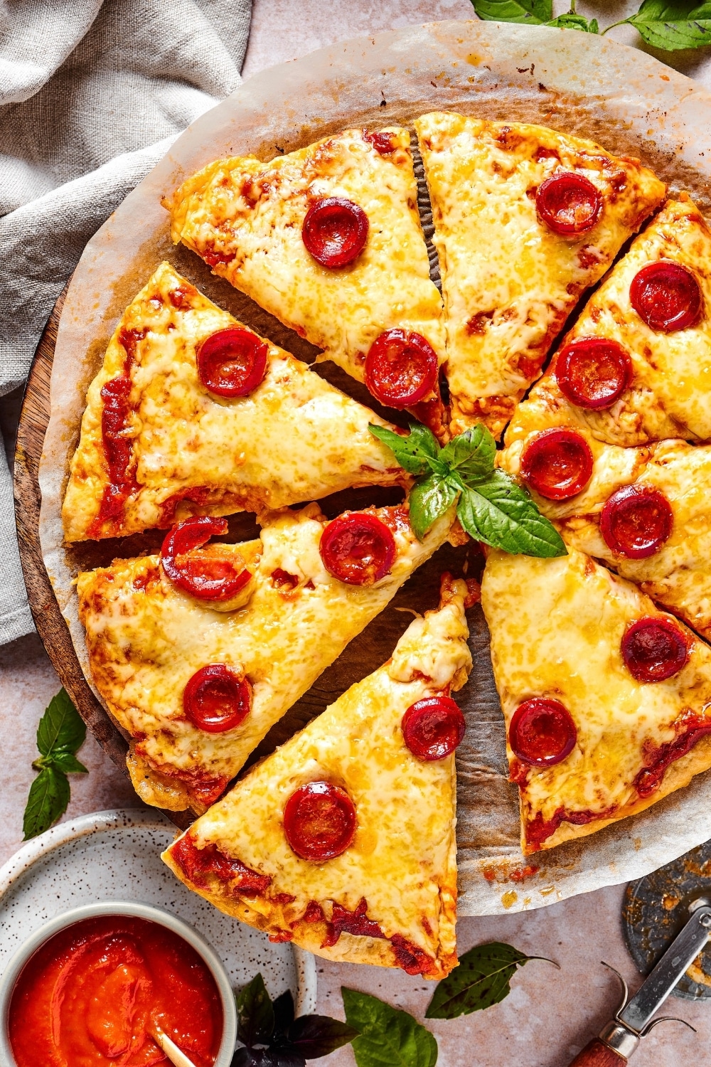 A cheese and pepperoni chicken crust pizza cut into 8 slices on a piece of parchment paper on a pizza tray.