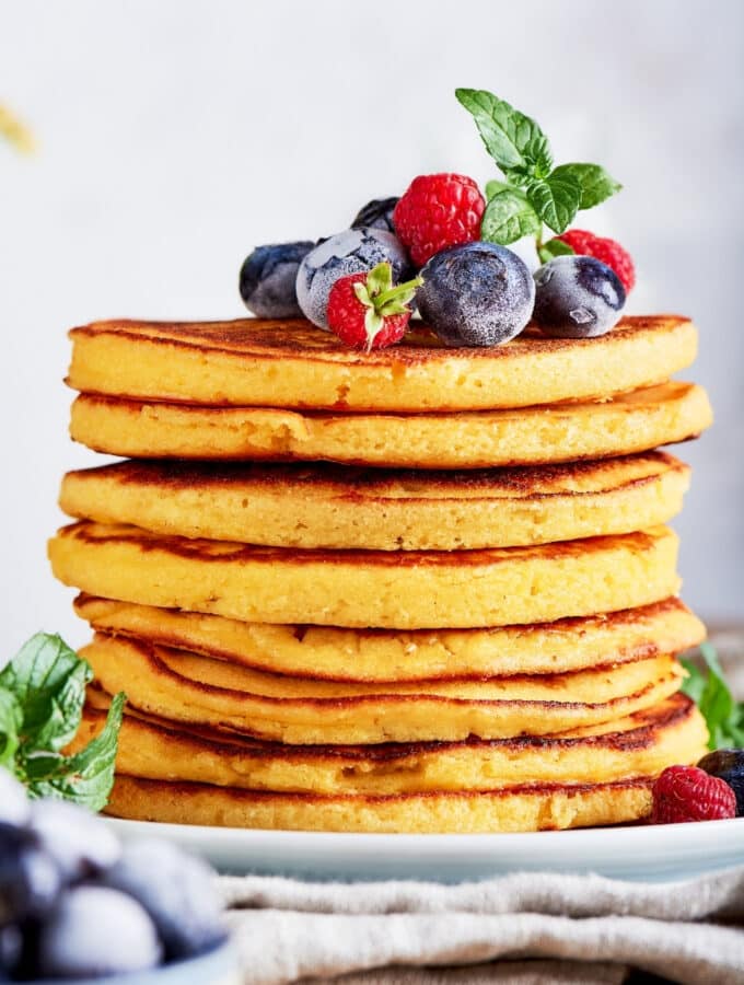 A stack of eight cream cheese pancakes on a white plate.