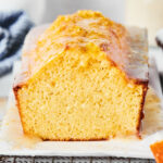 Pound cake loaf with a slice out of the front of it on a piece of parchment paper on a black wire rack.