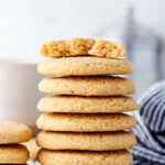 Hey stack of seven shortbread cookies on a wire rack. On the top cookie is a half of a shortbread cookie.