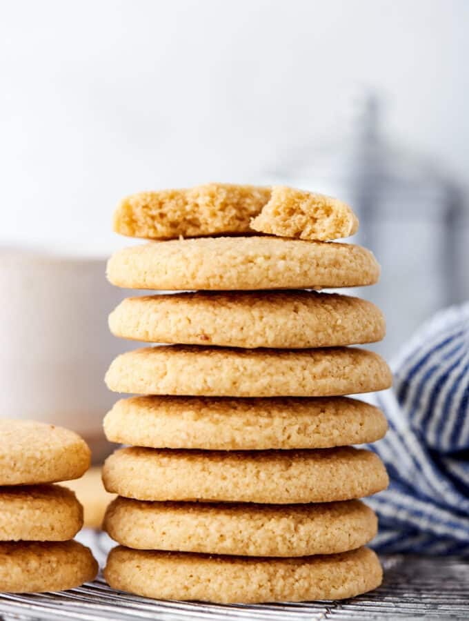 Hey stack of seven shortbread cookies on a wire rack. On the top cookie is a half of a shortbread cookie.