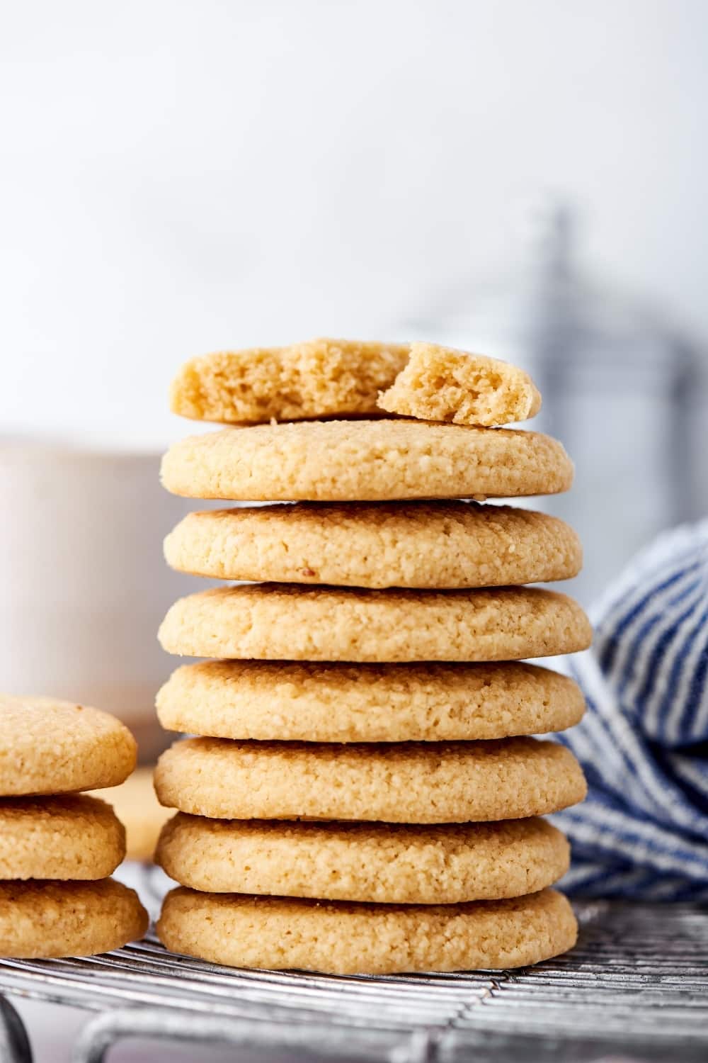 Hey stack of seven shortbread cookies on a wire rack. On the top cookie is a half of a shortbread cookie.