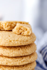 A stack of part of five shortbread cookies with a broken apart shortbread cookie on top.