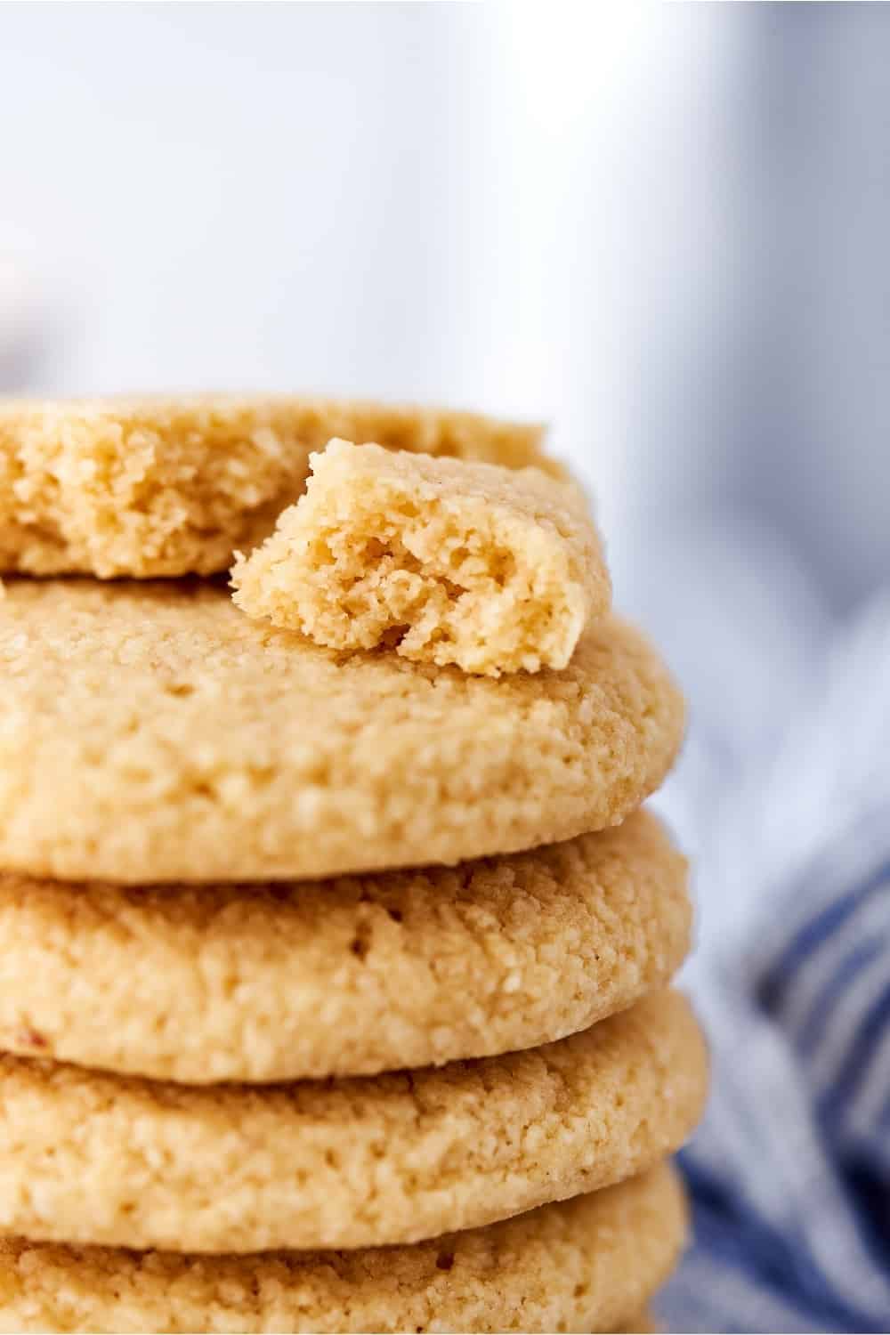 A stack of part of five shortbread cookies with a broken apart shortbread cookie on top.