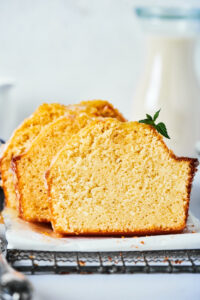 Three staggered slices of poundcake standing up right on a piece of parchment paper on black wire rack.