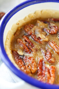 Part of a small bowl that has a mini pecan pie in it.