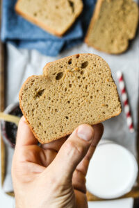 A hand holding a slice of nut butter bread.