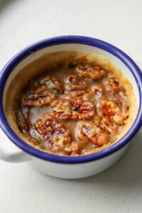 A mini pecan pie in a white bowl.