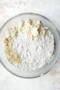 Dry ingredients inside of a glass bowl on a white table.