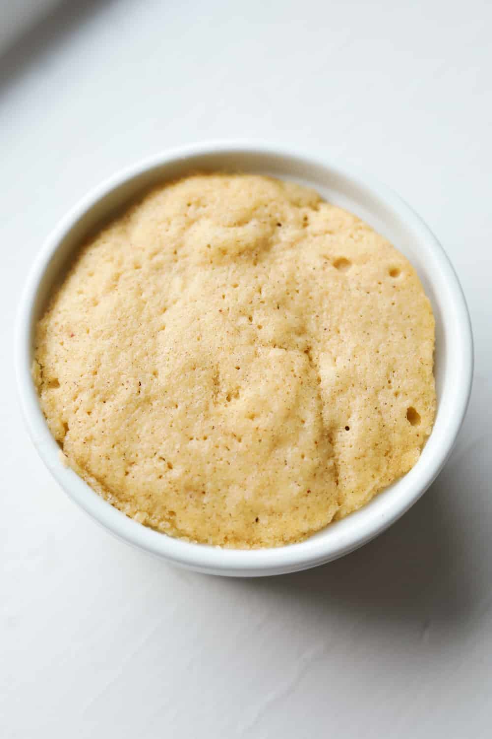 An apple spice cake inside of a white ramekin.