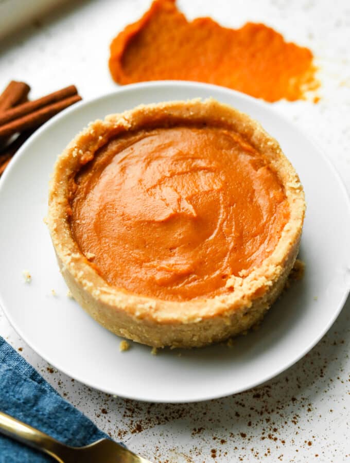 Pumpkin pie on a white plate. There's a blue napkin next to the plate.