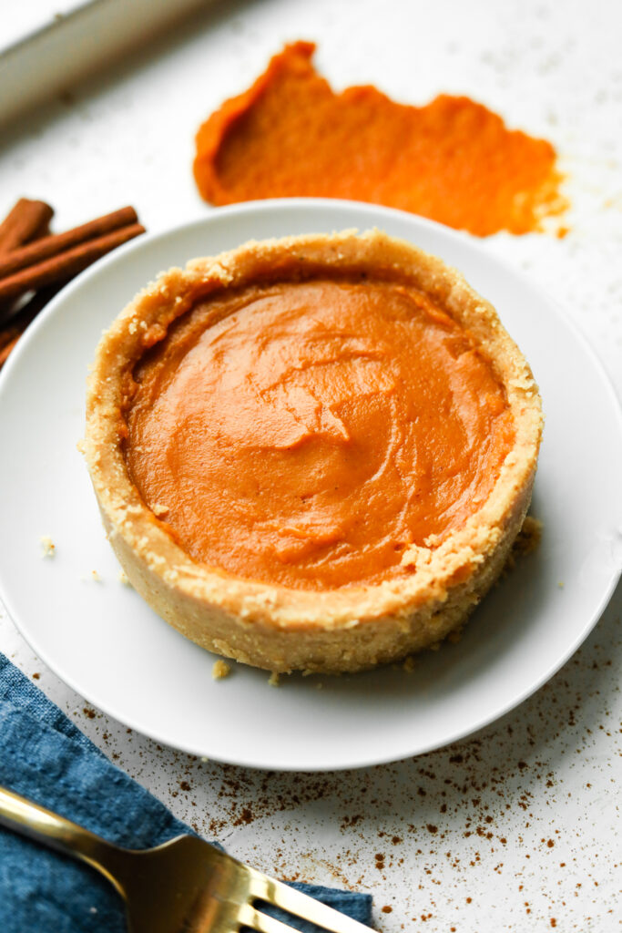 Pumpkin pie on a white plate. There's a blue napkin next to the plate.