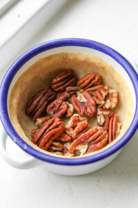 Pecans on top of a pie crust in a small bowl.