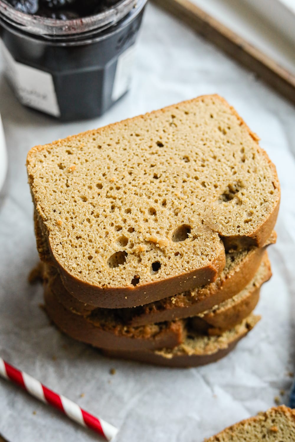 Four slices of nut butter bread stacked on top of each other.The bread is set on a baking sheet lined with parchment paper.