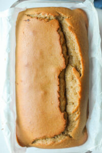 The top of a loaf of bread in a glass baking dish. There is a sheet of parchment paper underneath the bread.