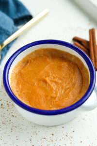 A white bowl with a blue rim and pumpkin pie inside of it.