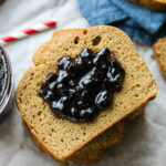 A slice of nut butter bread covered in grape jelly.