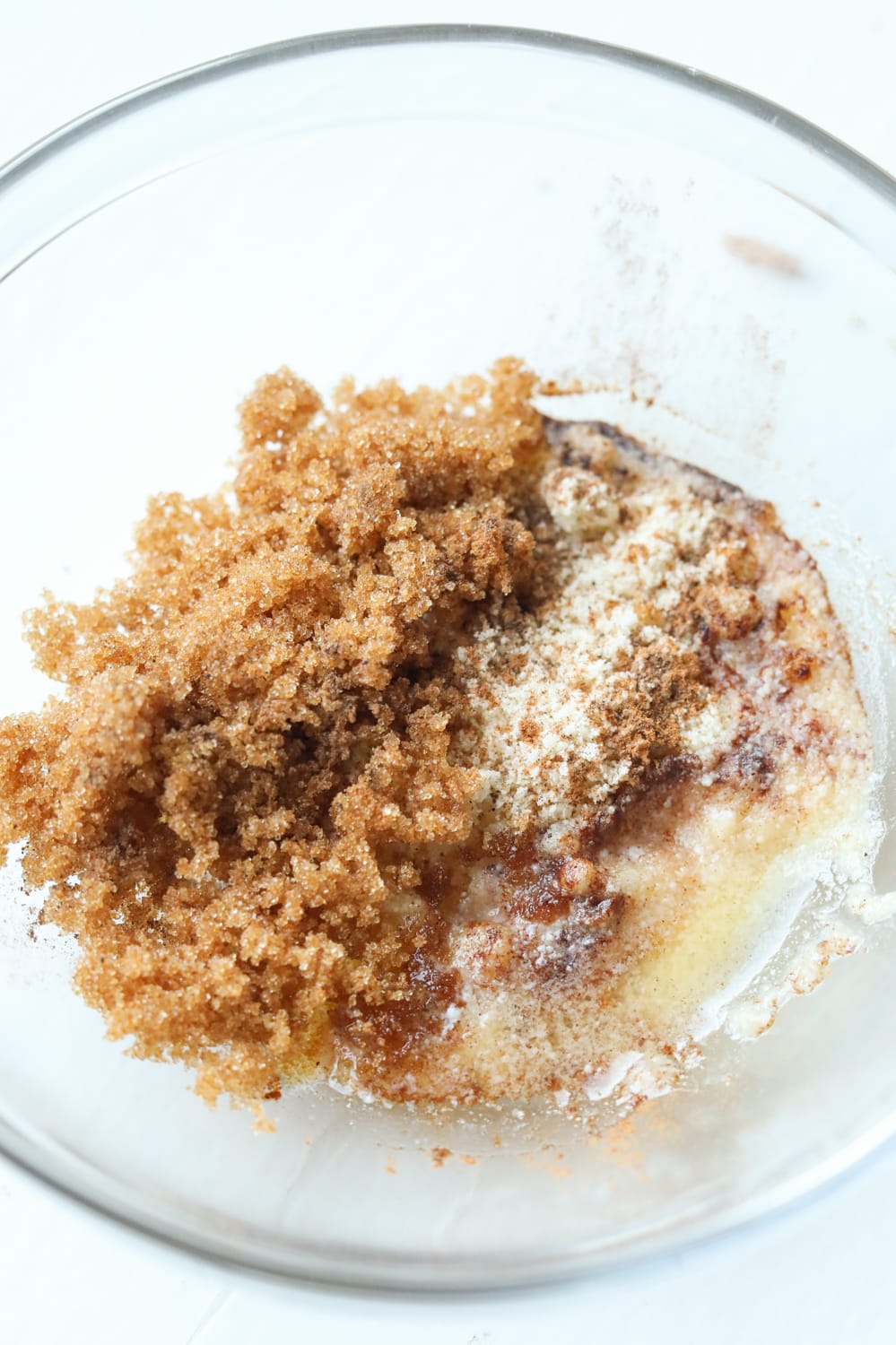 Wet and dry ingredients to make a spiced crumble inside of a glass bowl.