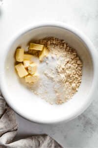 A white bowl with almond flour, erythritol, and cubed butter in it.