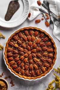 A pie dish filled with a pecan pie.