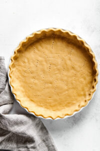 A pie crust and a pie dish on a white counter.