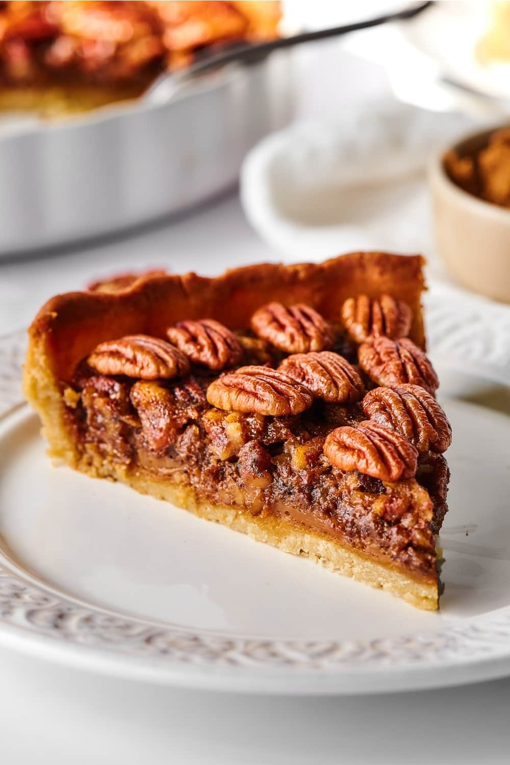 Hey slice of pecan pie on a white plate.