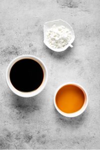 3 White ramekins with ingredients inside of them on a grey table.