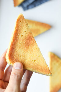 A hand holding a slice of toast.