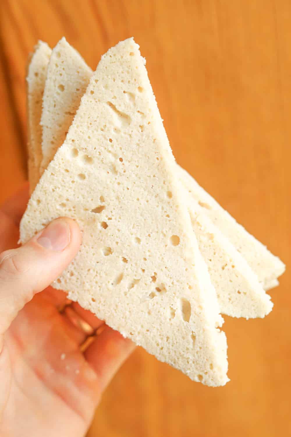 A hand holding four slices of white bread.