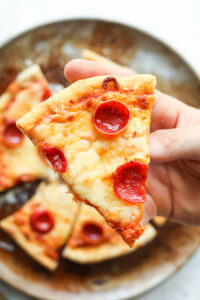 A hand holding a slice of cheese and pepperoni pizza.