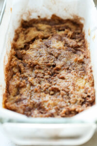 A glass bread pan lined with parchment paper, and bread batter is set in the pan.