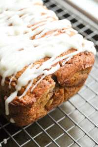 The side/end of a loaf of cinnamon swirl bread that is set on a drying rack.