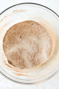 A glass bowl filled with cinnamon and a sugar substitute.