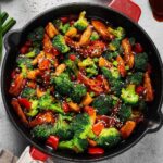 A cast iron pan filled with chicken stir fry.