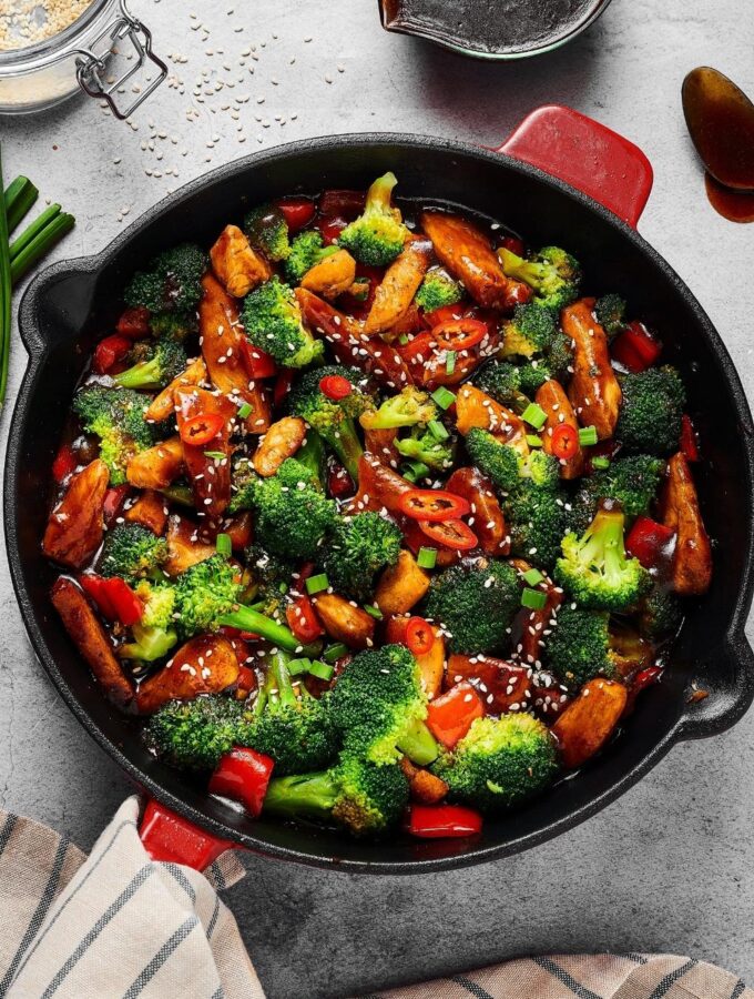 A cast iron pan filled with chicken stir fry.