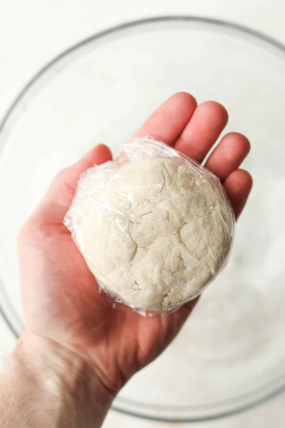 A ball of pizza dough wrapped in plastic wrap.