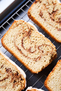 Slices of cinnamon swirl bread on a drying rack. The drying rack is set above a baking sheet.