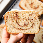 A hand holding a slice of cinnamon swirl bread.