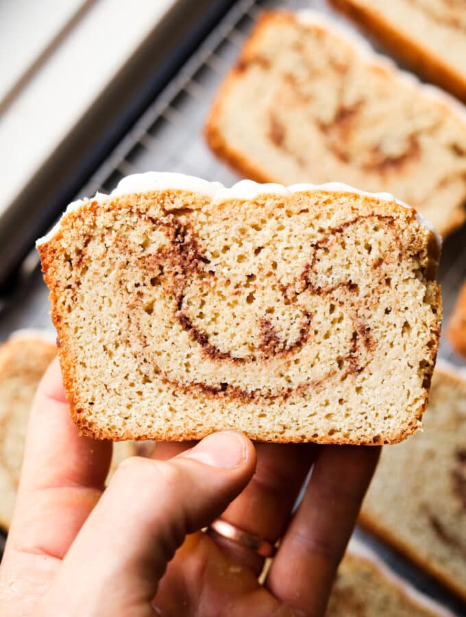 A hand holding a slice of cinnamon swirl bread.