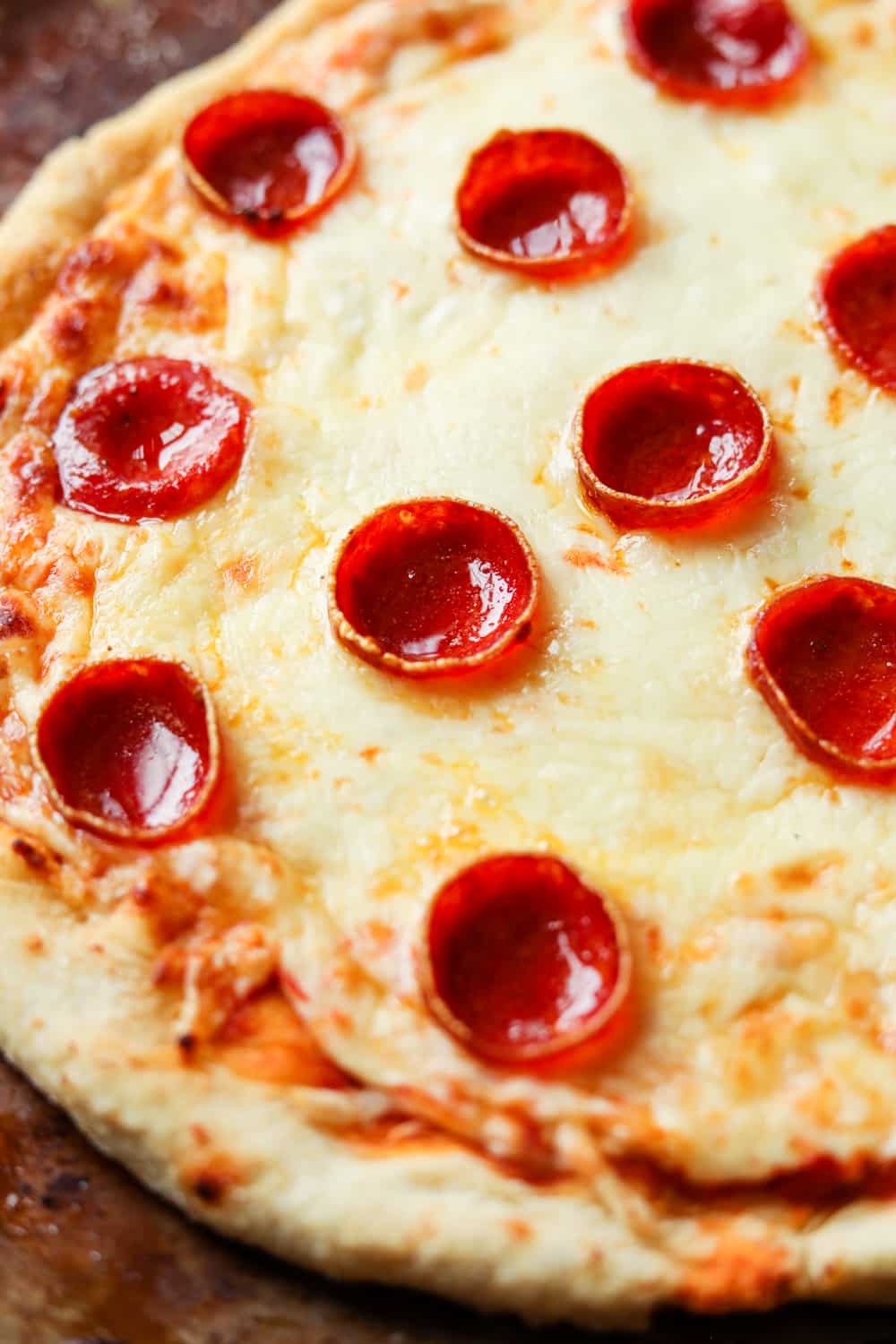 The middle of a cheese and pepperoni pizza. The pizza is set on a gray and brown tray.