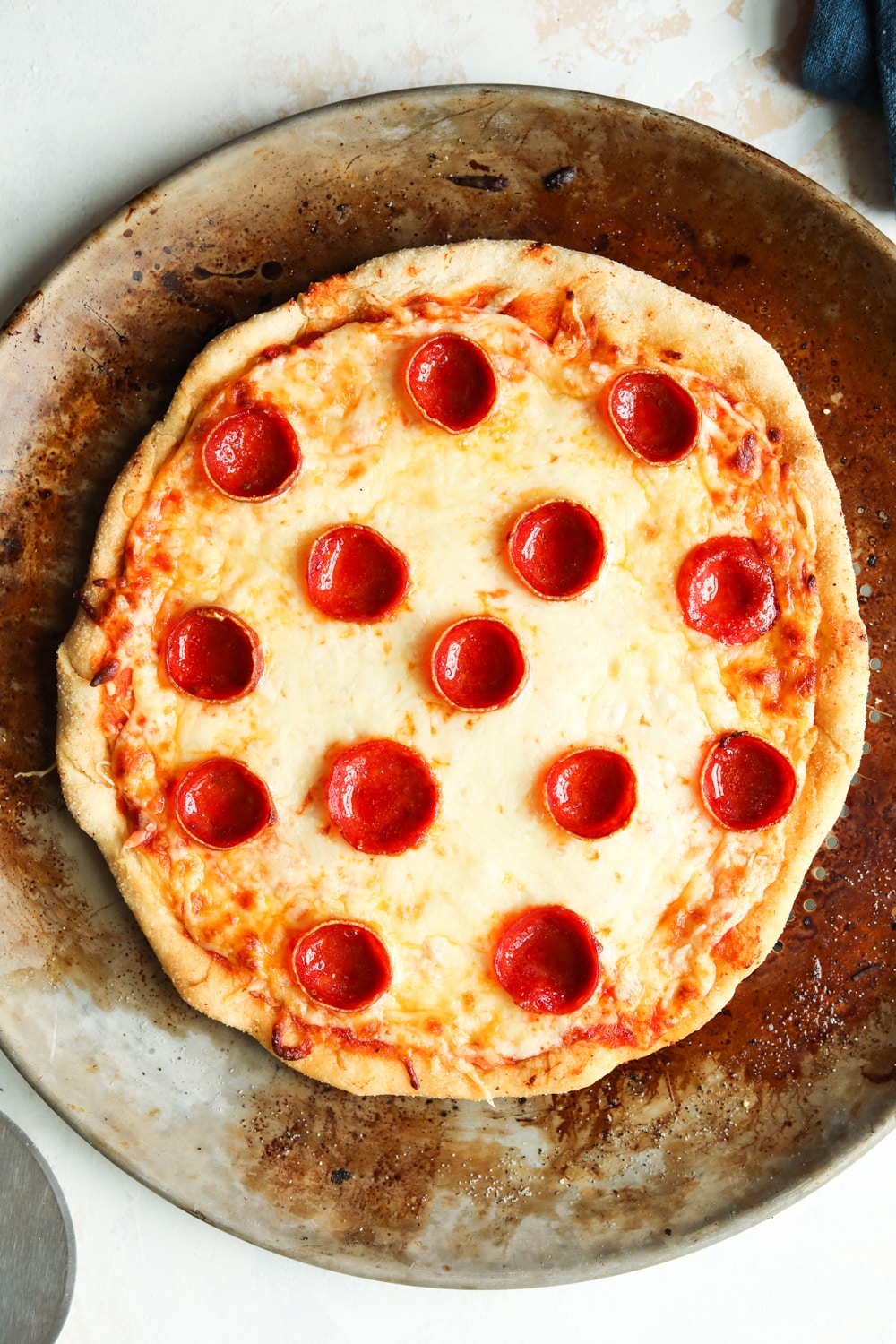 A cheese and pepperoni pizza set on a non-stick pizza tray.