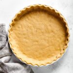 An almond flour pie crust in a white pie dish and a white counter.