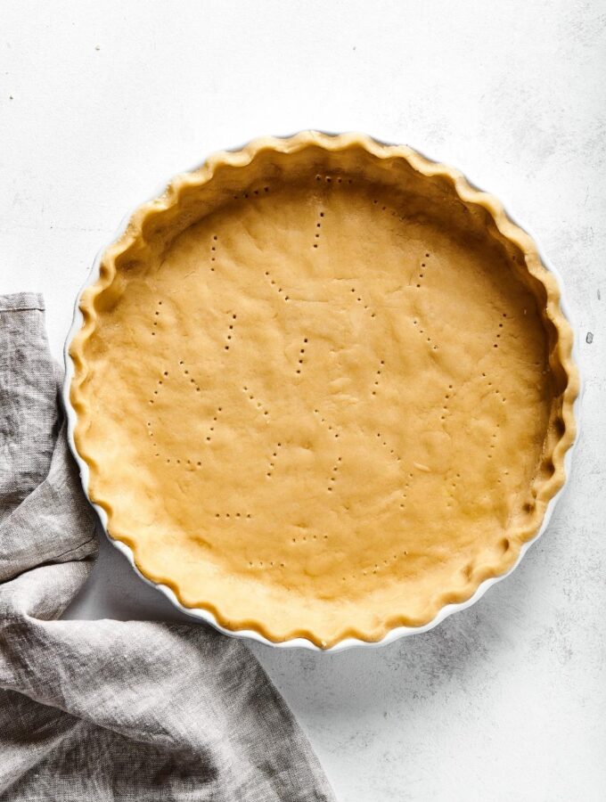 An almond flour pie crust in a white pie dish and a white counter.