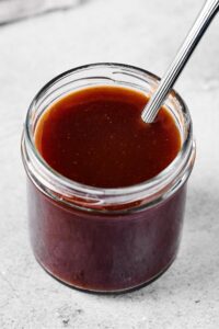 Stirfry sauce in a glass jar that is on a gray counter.