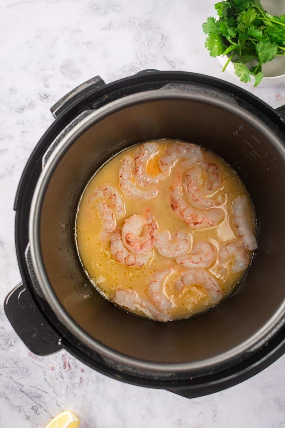An instant pot filled with shrimp and a marinade.