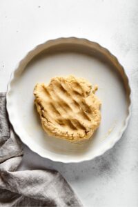 A bottle of almond flour pie crust though on a pie dish.