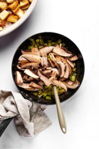 A skillet filled with chopped green peppers and onions.