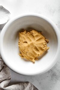 A white bowl filled with a ball of almond flour pie crust dough.